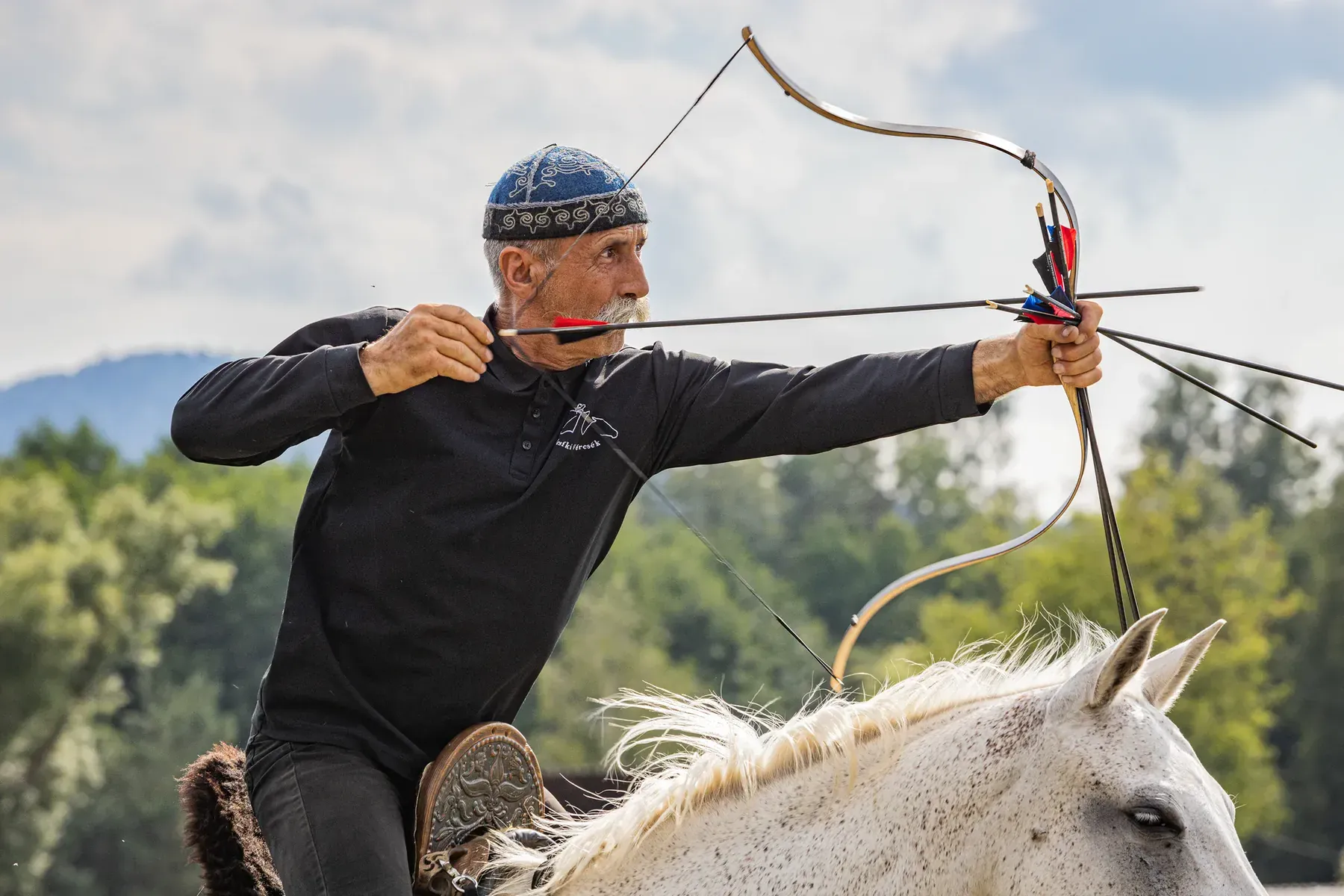 Un arcaș ecvestru întinde arcul în galop.